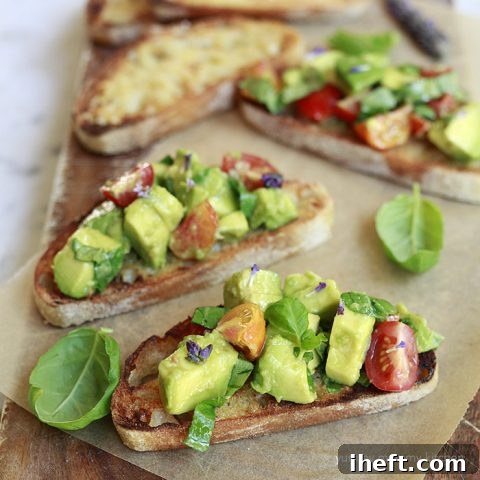 Beautifully plated avocado bruschetta toast, garnished with fresh basil, tomatoes, and a delicate drizzle of olive oil, ready for serving