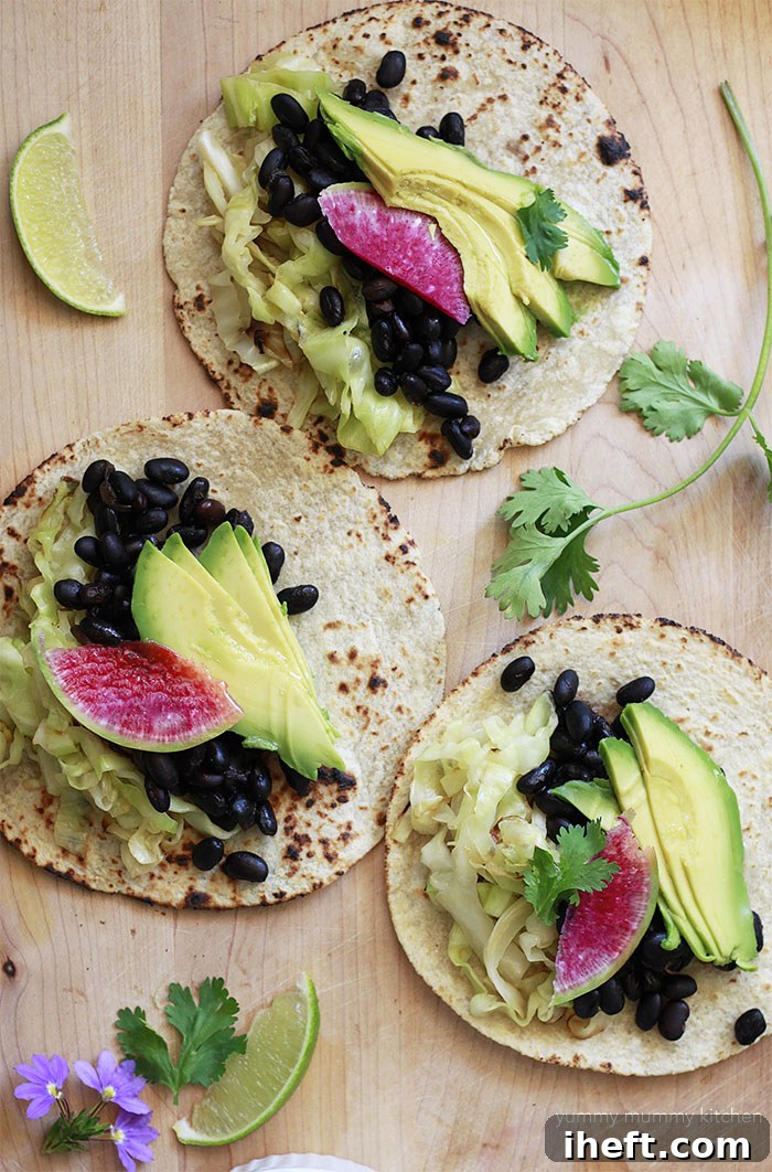 Delicious vegan tacos overflowing with black beans, tender sautéed cabbage, and fresh toppings