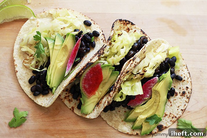 Close-up of vegetarian tacos featuring black beans, sautéed cabbage, and vibrant radish slices