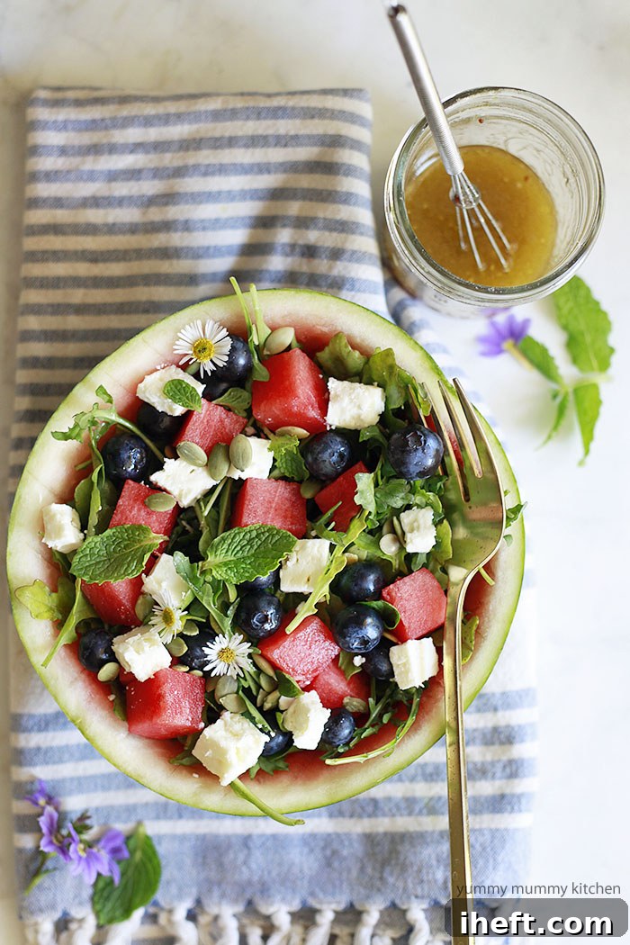 Beautifully arranged watermelon, feta, arugula, fresh mint, and blueberry salad presented elegantly in a festive watermelon bowl