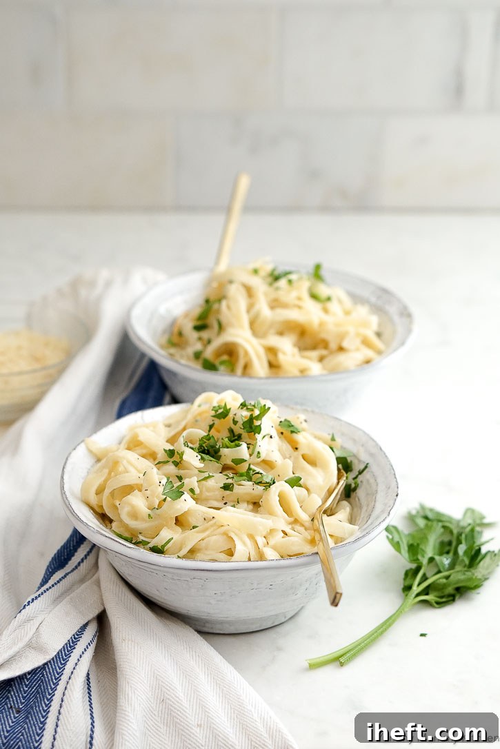 Bowls of delicious creamy vegan cauliflower fettuccini Alfredo topped with fresh parsley, ready to be enjoyed.