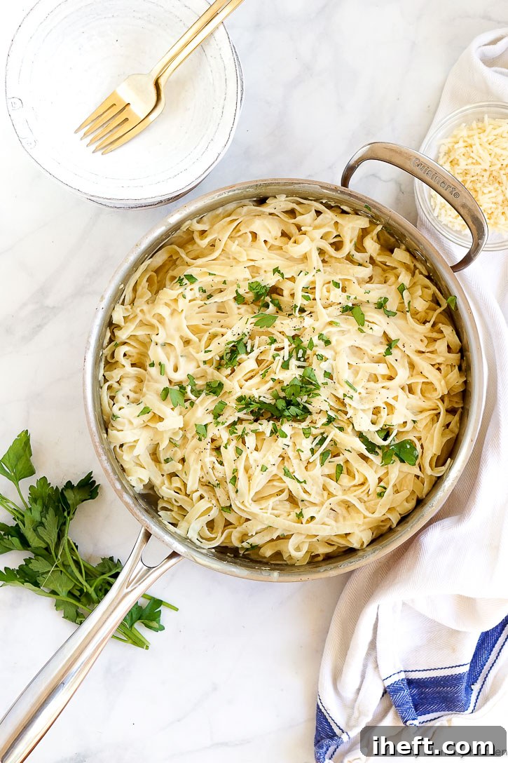 A close-up of a bowl of easy vegan cauliflower fettuccini Alfredo, showcasing its creamy texture and fresh parsley garnish.