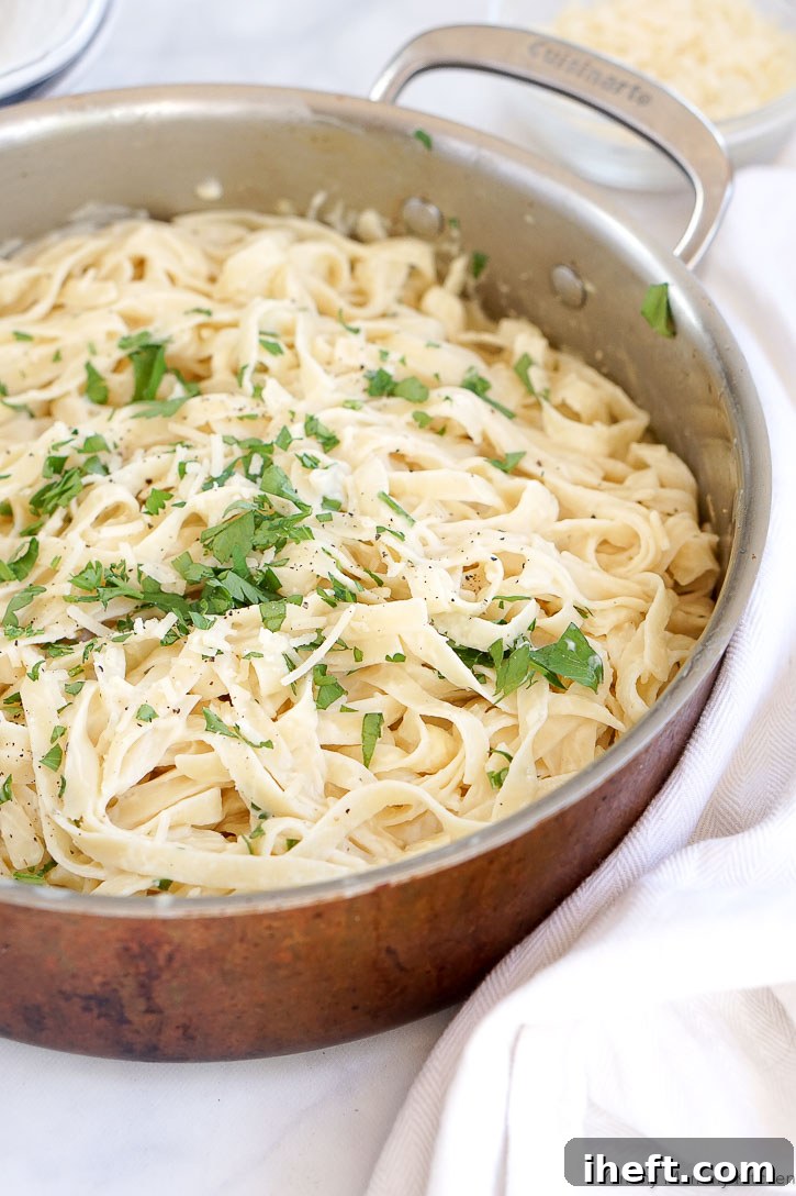 A close-up shot of creamy vegan cauliflower pasta sauce coating fettuccini noodles, garnished with parsley.