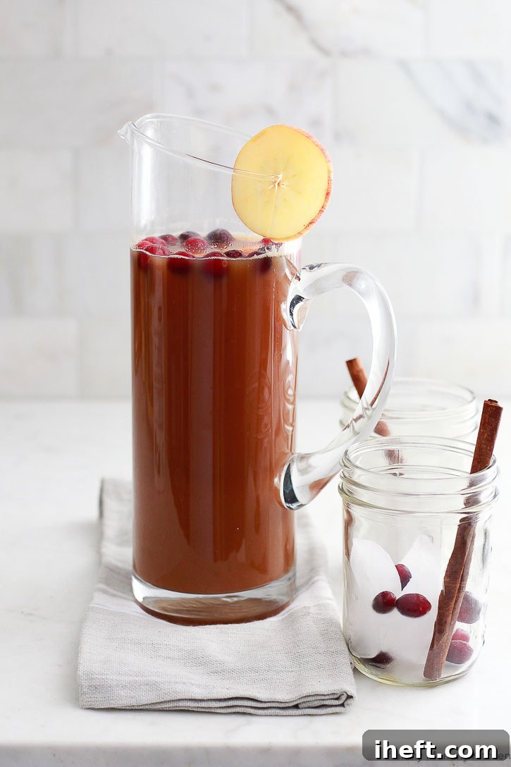 A beautiful pitcher of homemade apple cider, rich in color, sits ready to be served. Made effortlessly in a slow cooker.