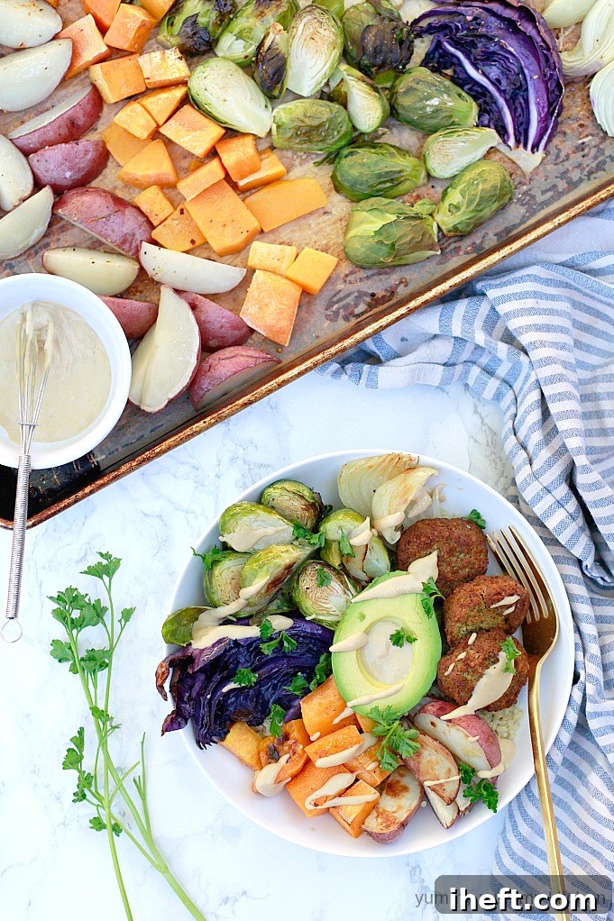 Colorful sheet pan roasted vegetables like broccoli, bell peppers, and sweet potatoes piled on a bed of quinoa with falafel, creamy avocado, and drizzled with a rich tahini sauce for a beautiful and healthy Buddha bowl.