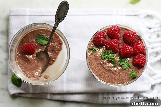 Beautiful bowls of rich cacao chia pudding garnished with vibrant fresh raspberries and a sprig of refreshing mint, showcasing a perfect healthy and delicious combination.