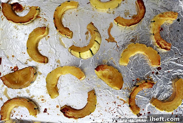 Roasted delicata squash slices cooling on a baking sheet