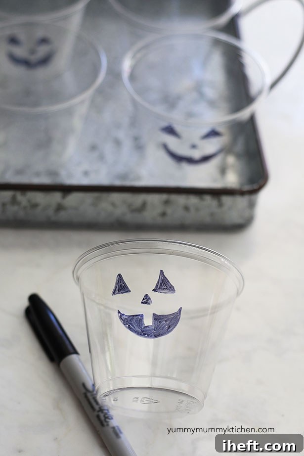 Jack-o'-lantern fruit cups in various stages of preparation