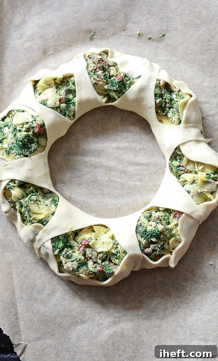 Hands shaping the puff pastry wreath, showing the filling being tucked in