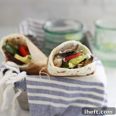 Two perfectly assembled vegetarian or vegan gyros, filled with an abundance of colorful grilled vegetables, nestled on warm flatbread.