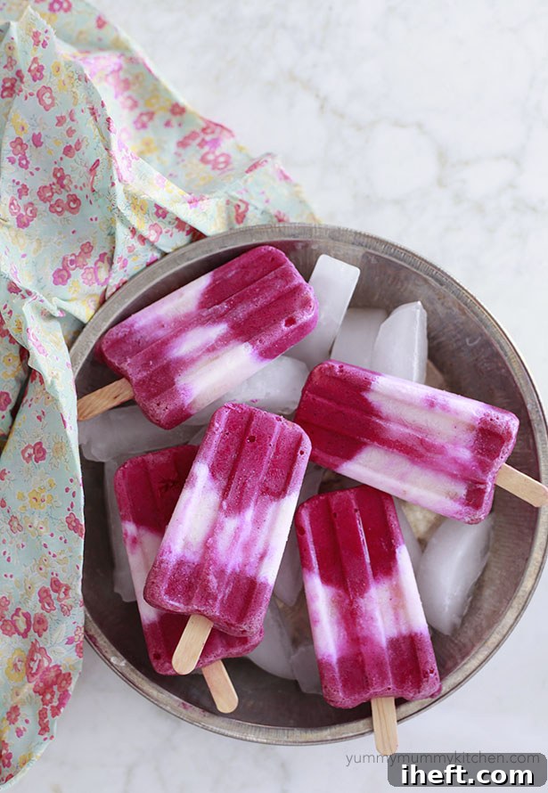 Beautiful pink and white dragon fruit popsicles in a dish on a white counter.