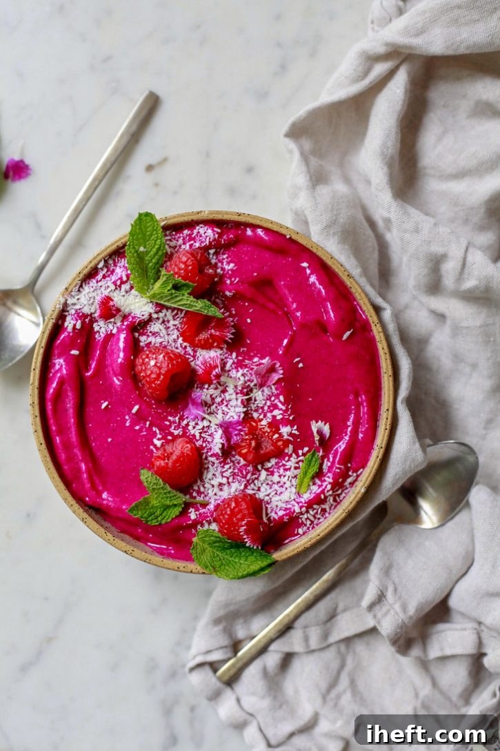 Two-toned pink and white pitaya popsicles with fruit in a white dish.