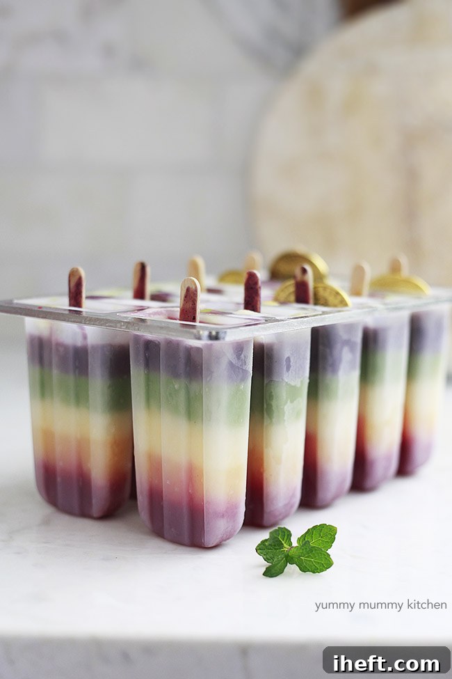 Popsicle molds with wooden sticks and layered tropical popsicles.