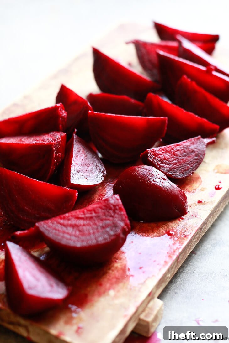 Freshly roasted beets peeled and quartered on a wooden cutting board.