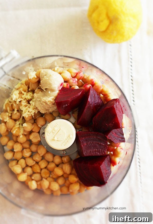 Chickpeas, garlic, tahini, beets, and lemon in a food processor ready to blend into beet hummus.