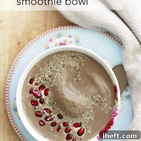 A creamy chocolate smoothie bowl topped with vibrant pomegranate seeds and nutritious hemp seeds, served in a rustic bowl.