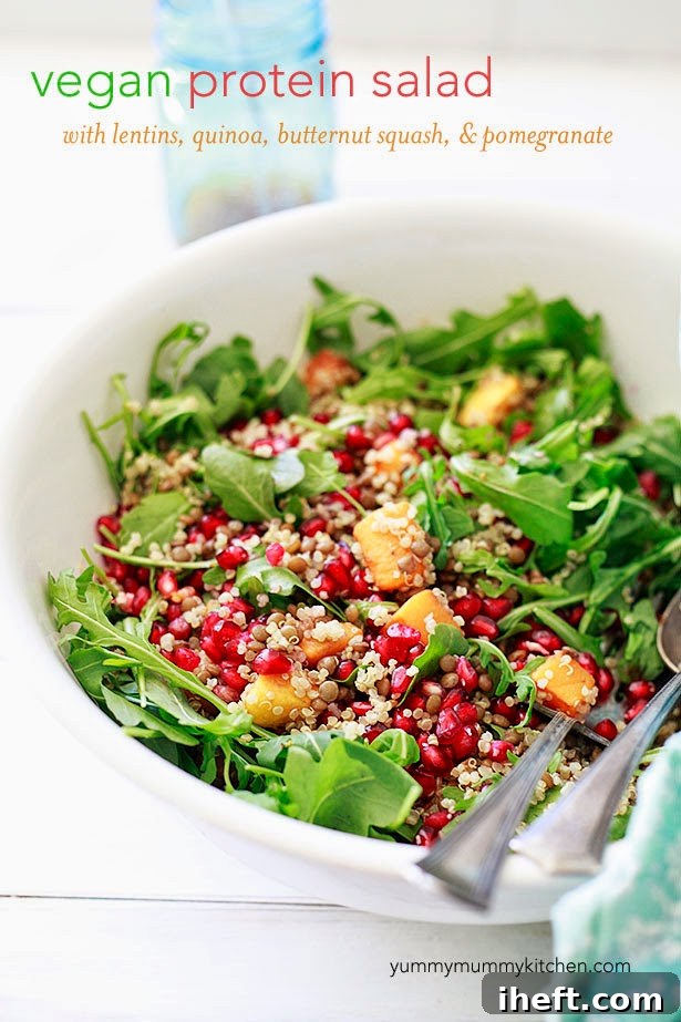 Vibrant high-protein vegan grain and legume salad featuring arugula, roasted butternut squash, quinoa, lentils, and fresh pomegranate seeds.