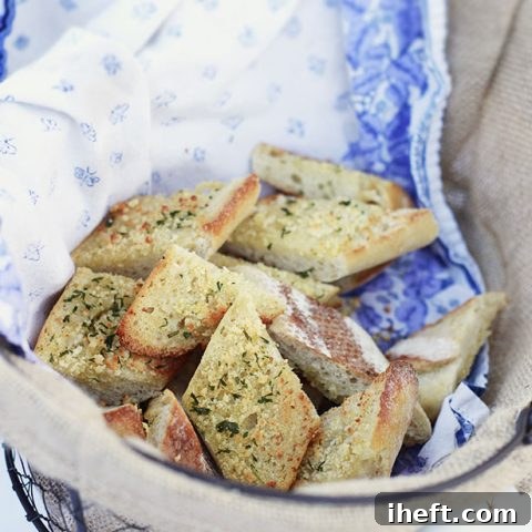A basket of freshly baked garlic bread, golden brown and garnished with parsley.