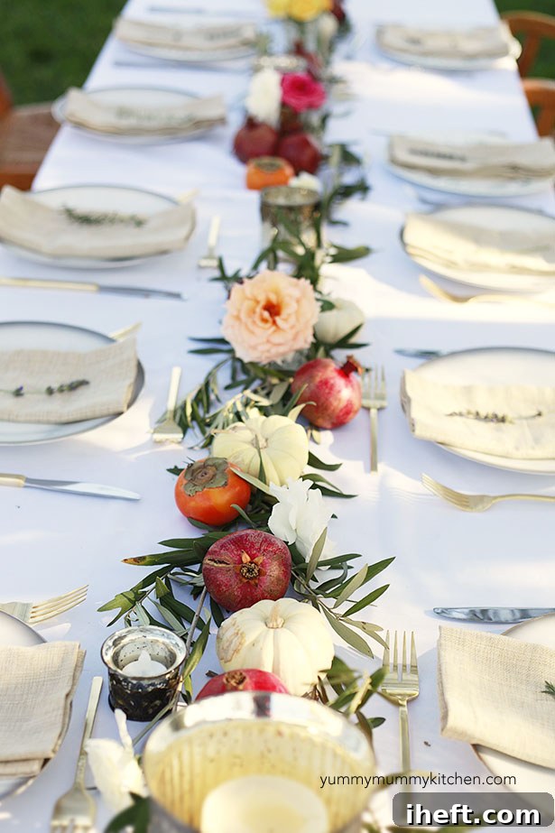 A beautiful dinner party table setting with olive branches, pumpkins, and pomegranates. Perfect for a Thanksgiving table. 