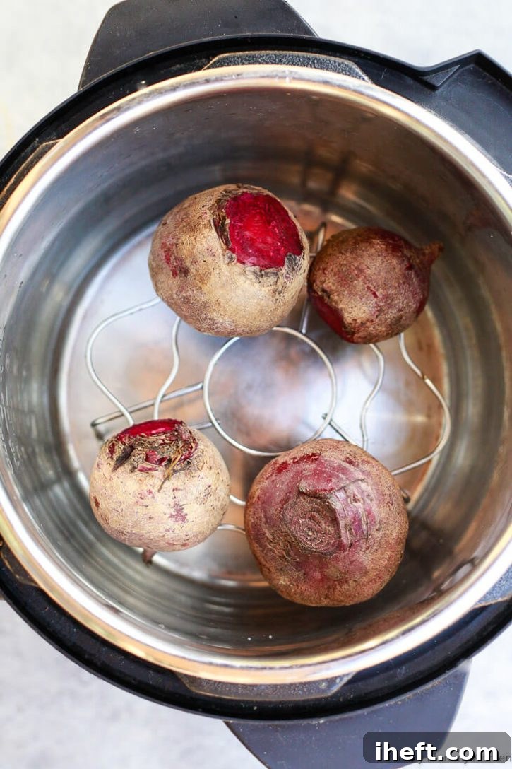 Three roasted beets, still whole, arranged on a rustic wooden surface.