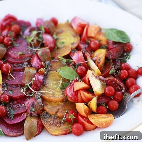 A vibrant roasted beet and heirloom tomato salad artfully arranged on a serving platter.