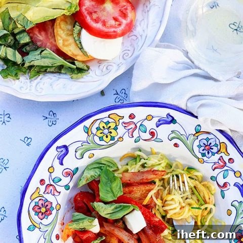 Delicious Italian peppers and onions served with fresh basil, creamy mozzarella, and a bed of zucchini noodles, showcasing a healthy and flavorful meal.