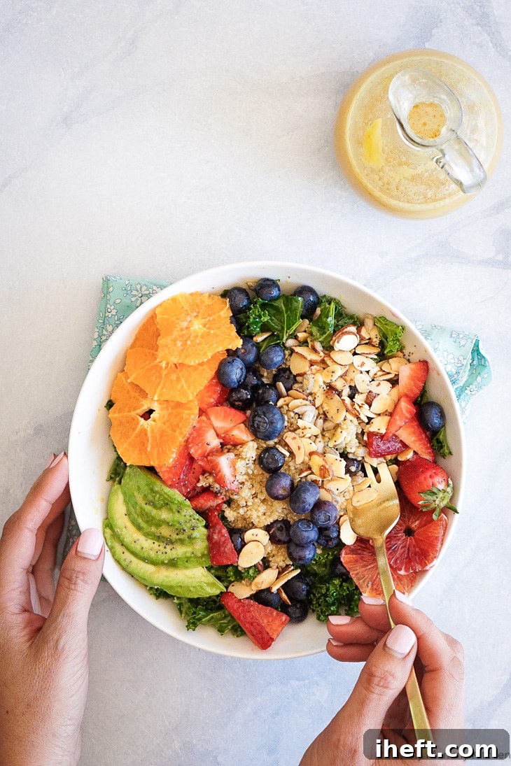 A beautiful healthy superfood salad featuring fresh kale, fluffy quinoa, mixed berries, creamy avocado, and slivered almonds, all drizzled with an easy homemade orange vinaigrette dressing made in a blender.