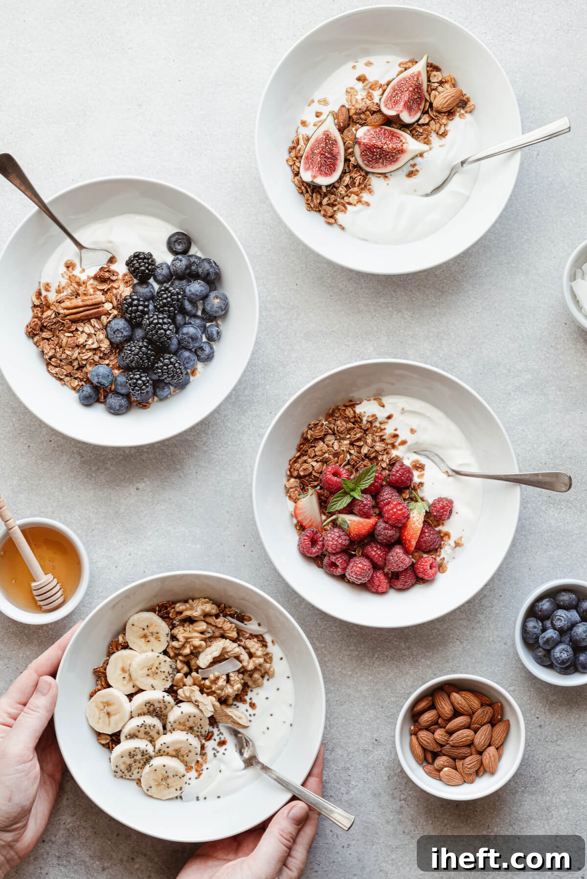Four bowls filled with yogurt, granola, and berries, bananas, and figs. A healthy breakfast idea.