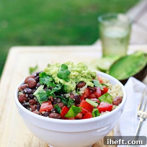 Vegan burrito bowl with quinoa, beans, tomatoes, lettuce, and easy guacamole.