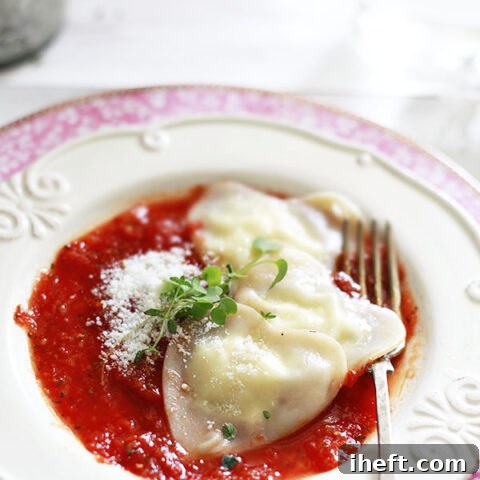 Heart-shaped cheese ravioli with wonton wrappers on a plate with tomato sauce.