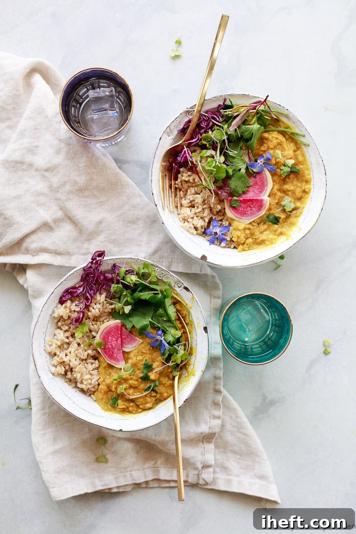 Two enticing bowls of red lentil masoor dal, served with fluffy brown rice and adorned with thinly sliced watermelon radish and vibrant fresh cilantro.