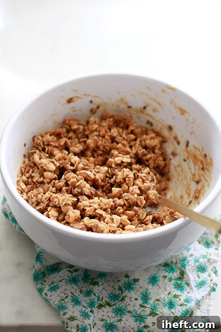 The ingredients for no-bake crunchy granola bars get mixed together in a white bowl. 