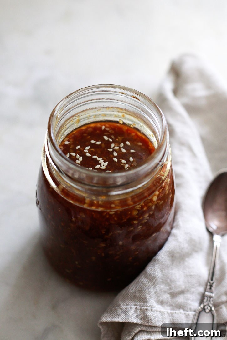 A clear glass jar filled with rich, dark homemade teriyaki sauce, beautifully showcased on a clean white kitchen counter. This image highlights the freshness and ease of making this vegan and gluten-free teriyaki sauce at home.