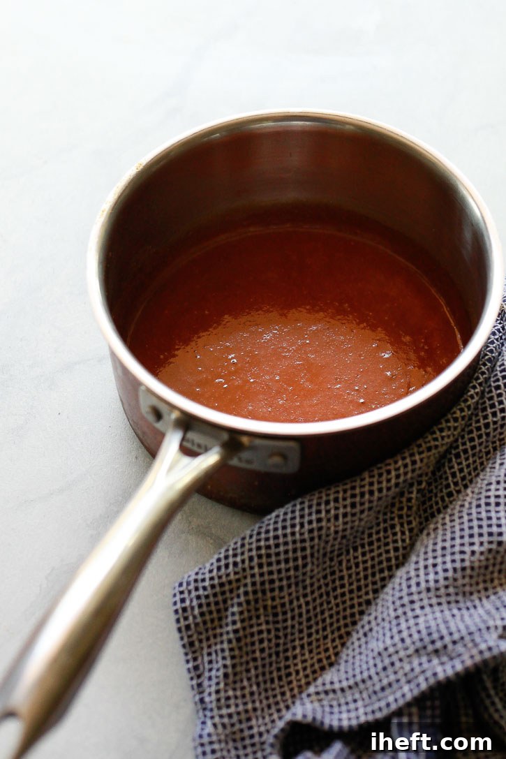 Homemade teriyaki sauce simmering gently in a small saucepan on the stove, beginning to visibly thicken into a beautiful, glossy glaze, demonstrating the final step in its preparation.