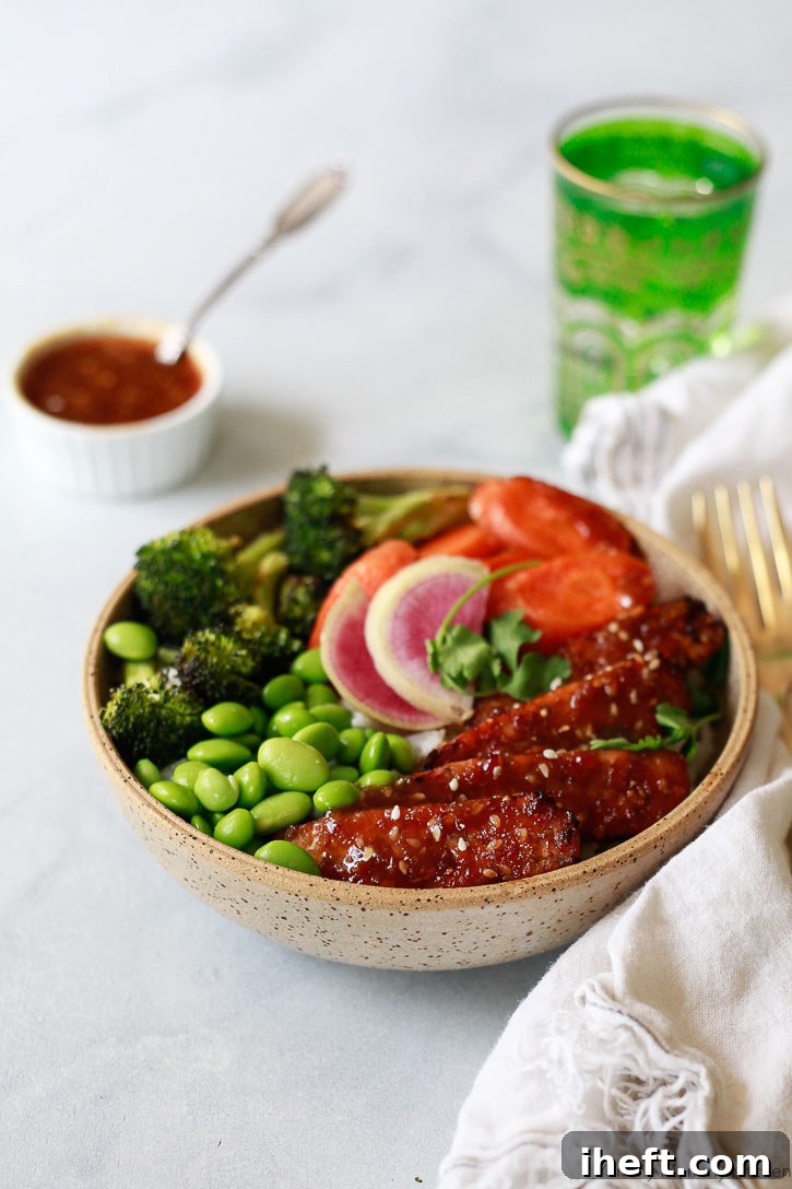 A vibrant, delectable vegan teriyaki tempeh bowl, featuring beautifully glazed tempeh, fresh, colorful vegetables, and fluffy rice, all generously drizzled with homemade teriyaki sauce, illustrating a perfect meal idea.
