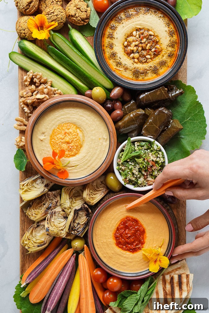A vibrant and beautifully arranged mezze platter featuring creamy hummus, an assortment of crisp cold vegetables, golden-brown falafel, and warm flatbread slices. This impressive appetizer board is ideal for lively parties and sophisticated gatherings.