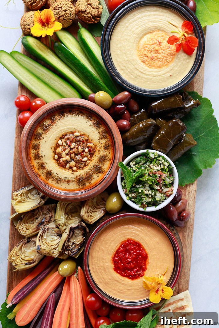 A stunning hummus platter showcasing elegant bowls of creamy hummus, refreshing tabbouleh, a colorful array of fresh vegetables, and savory falafel. This presentation offers a perfect Mediterranean Greek appetizer that is both vegetarian and vegan-friendly, ideal for diverse palates.