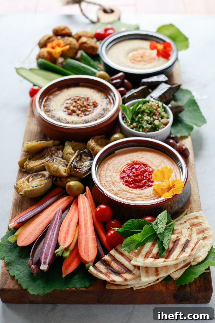 A captivating mezze appetizer platter, generously laden with creamy hummus, vibrant rainbow carrots, soft flatbread, succulent marinated artichokes, and savory falafel, presenting an ideal vegetarian or vegan party centerpiece for any gathering.