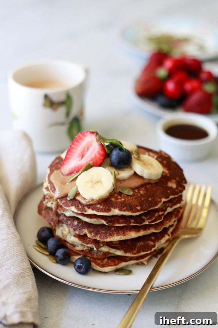 A visually appealing stack of vegan banana pancakes generously topped with an assortment of fresh berries and banana slices, highlighting the deliciousness of this easy plant-based breakfast recipe.