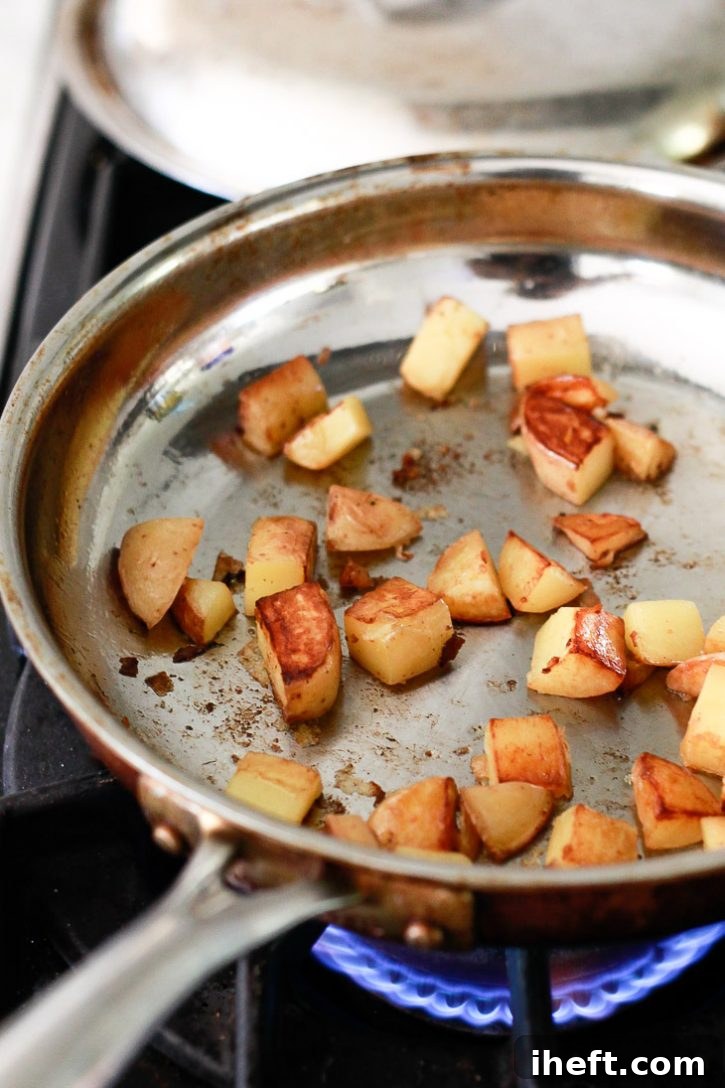 Baby yellow potatoes roast in a frying pan on the stove before going into a vegan breakfast burrito. 