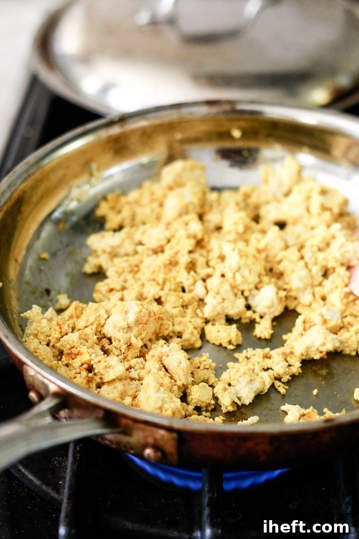 Tofu scramble cooking in a frying pan for vegan breakfast burritos. 