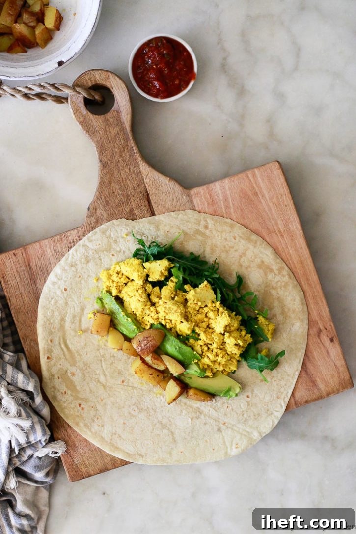 Tofu scramble, arugula, avocado, and potatoes go into a tortilla for this vegan breakfast burrito recipe. 