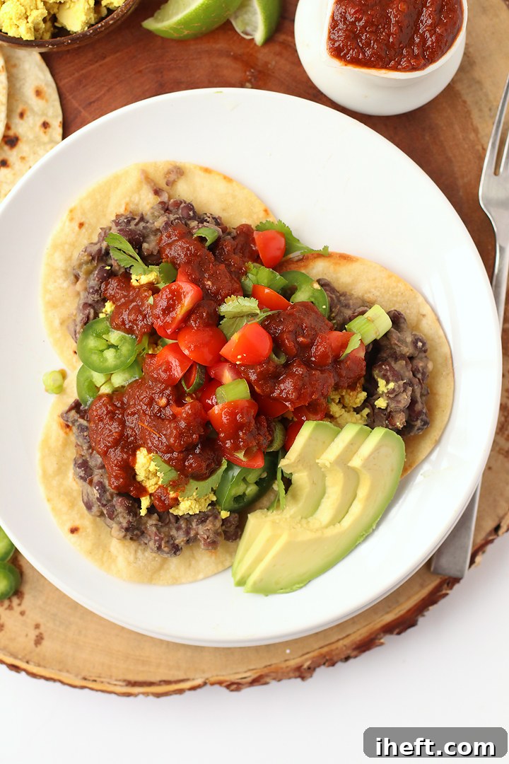 Hearty vegan huevos rancheros with scrambled tofu, refried beans, and spicy sauce.