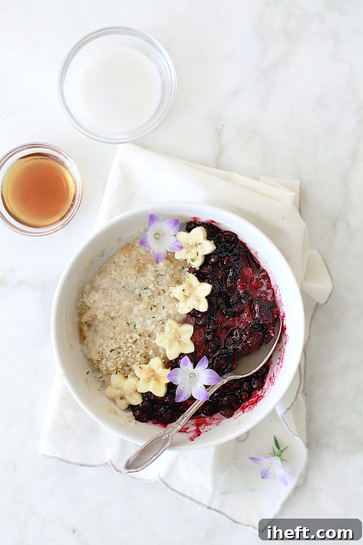 A superfood breakfast quinoa bowl topped with blueberry sauce and fresh fruit.