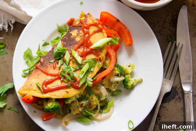 A vibrant veggie-stuffed vegan omelet made from chickpea flour, showcasing a delicious egg-free alternative.