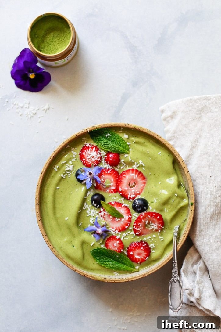 Beautiful matcha banana smoothie made with matcha powder. This vegan matcha green tea smoothie bowl is made with almond milk and topped with strawberries, blueberries, and coconut shreds.