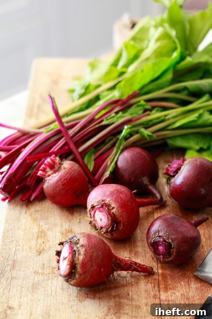 Beet greens being carefully trimmed from the beet roots on a cutting board before roasting.
