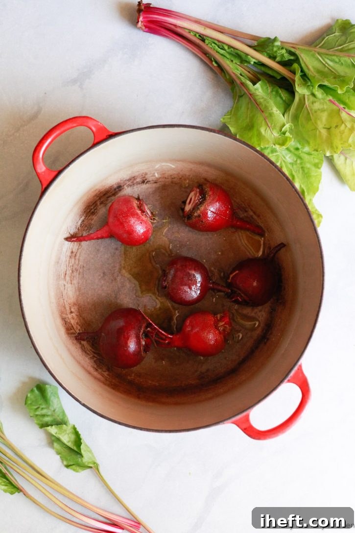 Raw beet roots are placed in a durable Dutch oven and drizzled with olive oil, ready for foil-free oven roasting.