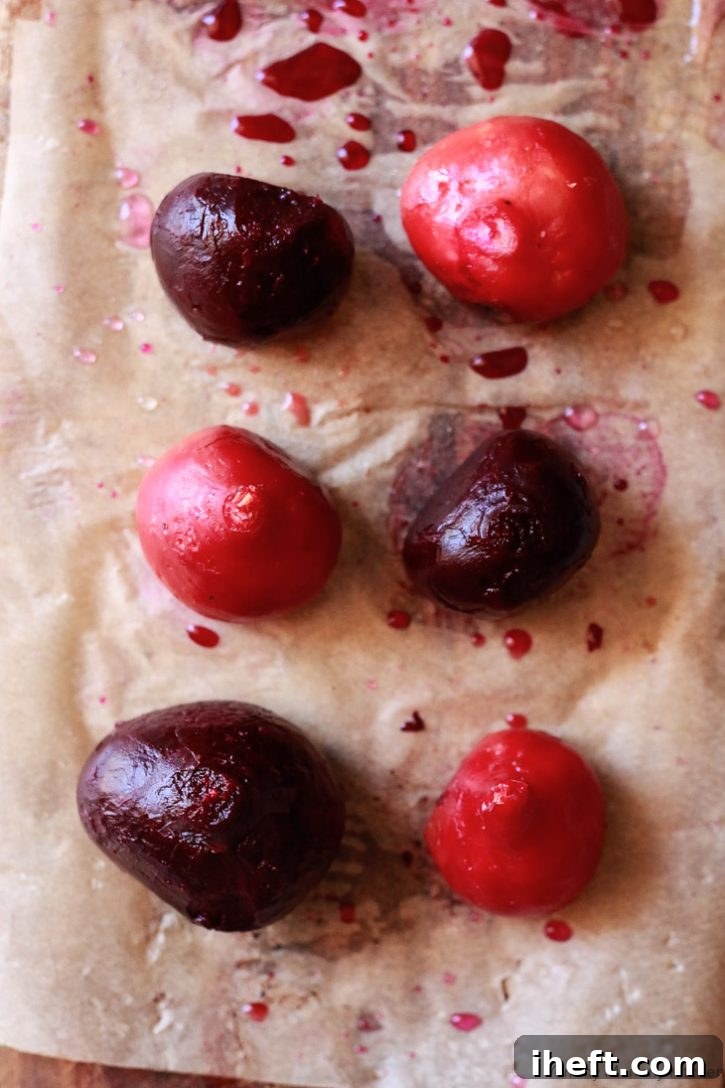 Peeled and whole roasted candy cane and purple beets resting on a cutting board, ready to be sliced.