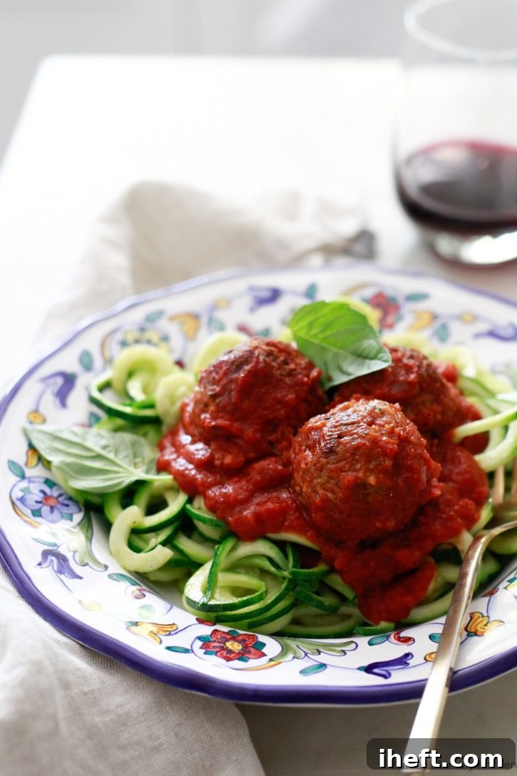 A plate of vegan meatless meatballs with marinara sauce on zucchini noodles. 